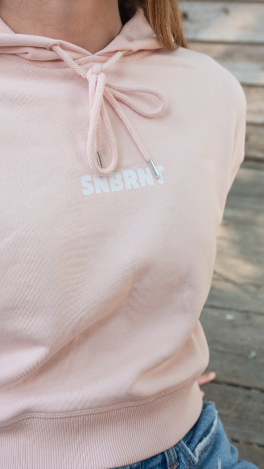 Person wearing a light pink CROPPED hoodie with 'SNBRNT' text