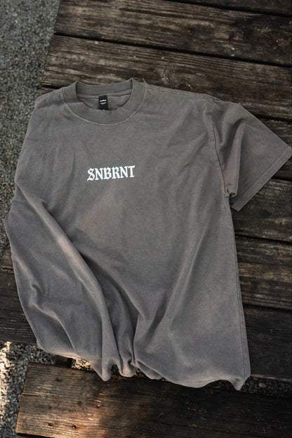 Gray t-shirt with 'SNBRNT' logo on a wooden surface