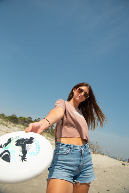 Woman on a beach holding a frisbee with a clear blue sky in the background